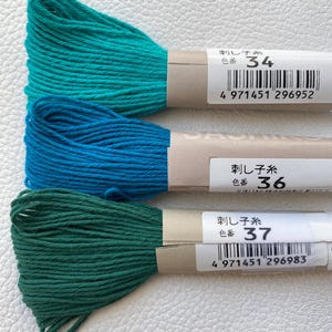 May include: Three spools of embroidery floss in shades of teal, blue, and green. Each spool has a label with the text "刺し子糸" and a number: 34, 36, and 37.