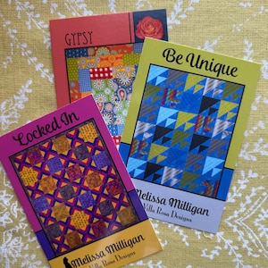 May include: Three quilting pattern cards with colorful quilt designs. The cards are titled "Gypsy", "Be Unique", and "Locked In". The cards are designed by Melissa Milligan for Villa Rosa Designs.