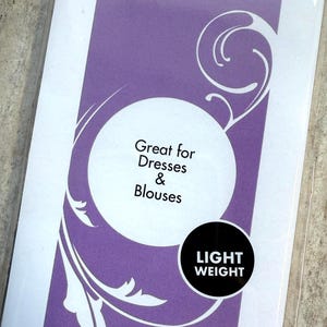 Op de afbeelding: Een rechthoekige paars-witte productverpakking met het label IRON-ON, witte tekst Great for Dresses & Blouses in een witte cirkel en een zwarte cirkel met de witte tekst LIGHT WEIGHT. Het ontwerp bevat witte krulpatronen.