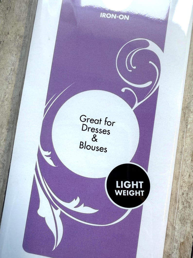 Op de afbeelding: Een rechthoekige paars-witte productverpakking met het label IRON-ON, witte tekst Great for Dresses & Blouses in een witte cirkel en een zwarte cirkel met de witte tekst LIGHT WEIGHT. Het ontwerp bevat witte krulpatronen.