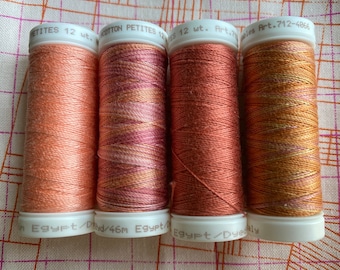May include: Four spools of cotton thread in shades of orange, pink, and brown. The spools are labeled "Cotton Petites 12 wt. Art. 712-4066" and "Egypt/Dyed/46m Egypt/Dyeonly".