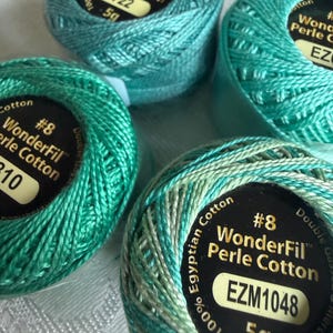 May include: Four spools of WonderFil #8 Perle Cotton thread in various shades of teal and green. Each spool is labeled 100% Egyptian Cotton, 5g, and features specific color codes including 722 and EZM1048 on black circular labels.