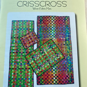 May include: Aunties Two Patterns Crisscross Woven Fabric Mats. The image shows a pattern for woven fabric mats. The mats are rectangular and square, with a colorful woven design in shades of green, red, blue, and yellow.