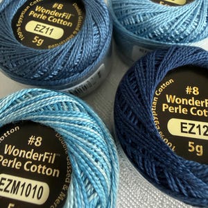 May include: Four spools of WonderFil #8 Perle Cotton thread in various shades of blue. Each spool is labeled 100% Egyptian Cotton, double gassed and mercerized, with 5g weight. The labels display color codes EZ11, 716, EZ12, and EZM1010.