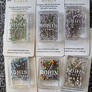 May include: A set of 10 packs of Bohin glass head pins. Each pack contains 80 pins with different colored glass heads. The pins are 30 mm (1 1/4 inches) long and made of nickel-plated steel.