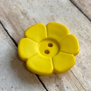 May include: A bright yellow plastic flower-shaped button with two holes.