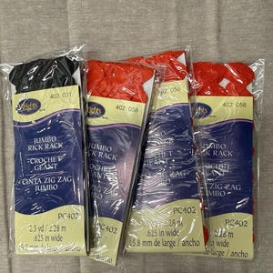 May include: Four packages of Wrights jumbo rick rack trim in clear plastic sleeves. One package contains black trim, and three packages contain red trim. Each label displays the text Jumbo Rick Rack, 2.5 yd, and .625 in wide, model PC402.