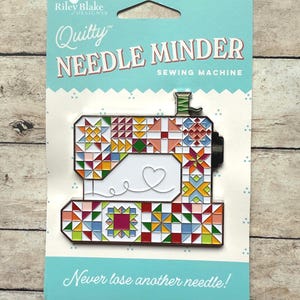 May include: A white and blue card with a colorful sewing machine design. The card reads "Quilty Needle Minder Sewing Machine" and "Never lose another needle!"