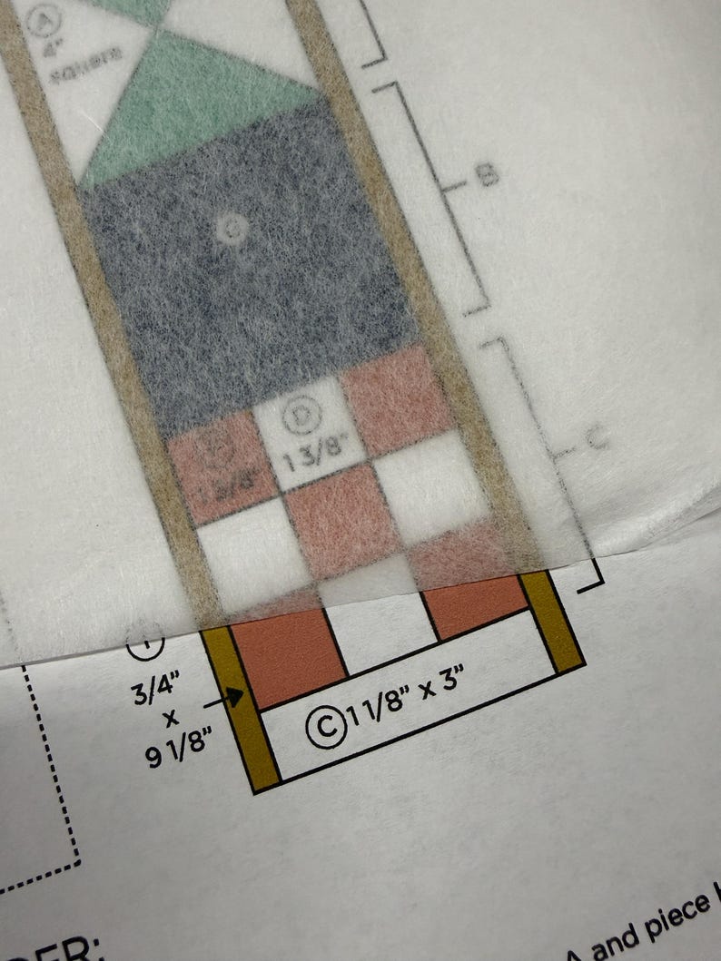 Op de afbeelding: Een naaipatroon gedrukt op papier met een doorschijnende overlay. Het patroon bevat geometrische vormen gelabeld A, B, C en D, met gedrukte afmetingen waaronder 4 inch, 1 3/8 inch, 3/4 inch bij 9 1/8 inch en 1 1/8 inch bij 3 inch.