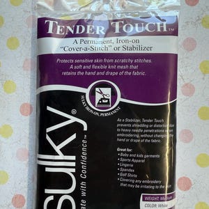 May include: A package of Sulky Tender Touch stabilizer. The package is black and purple with white text, including "Tender Touch" and "Sulky." The stabilizer is white, measures 20" x 36", and is designed to protect sensitive skin from scratchy stitches.