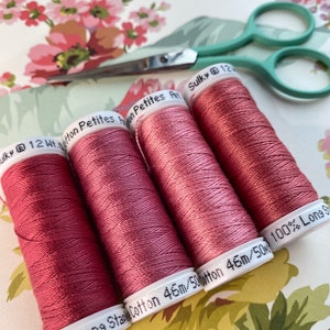 May include: Four spools of Sulky 12wt Cotton Petites thread in a dusty rose color. The spools are labeled "100% Long Staple Cotton 46m/50wt" and "Sulky 12wt Cotton Petites".