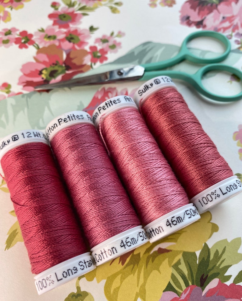 May include: Four spools of Sulky 12wt Cotton Petites thread in a dusty rose color. The spools are labeled "100% Long Staple Cotton 46m/50wt" and "Sulky 12wt Cotton Petites".