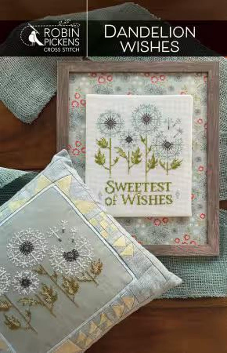 May include: A framed cross-stitch featuring dandelions with the text "Sweetest of Wishes." A matching pillow with a dandelion design is in the foreground. The image also includes the text "Dandelion Wishes" and the Robin Pickens Cross Stitch logo.
