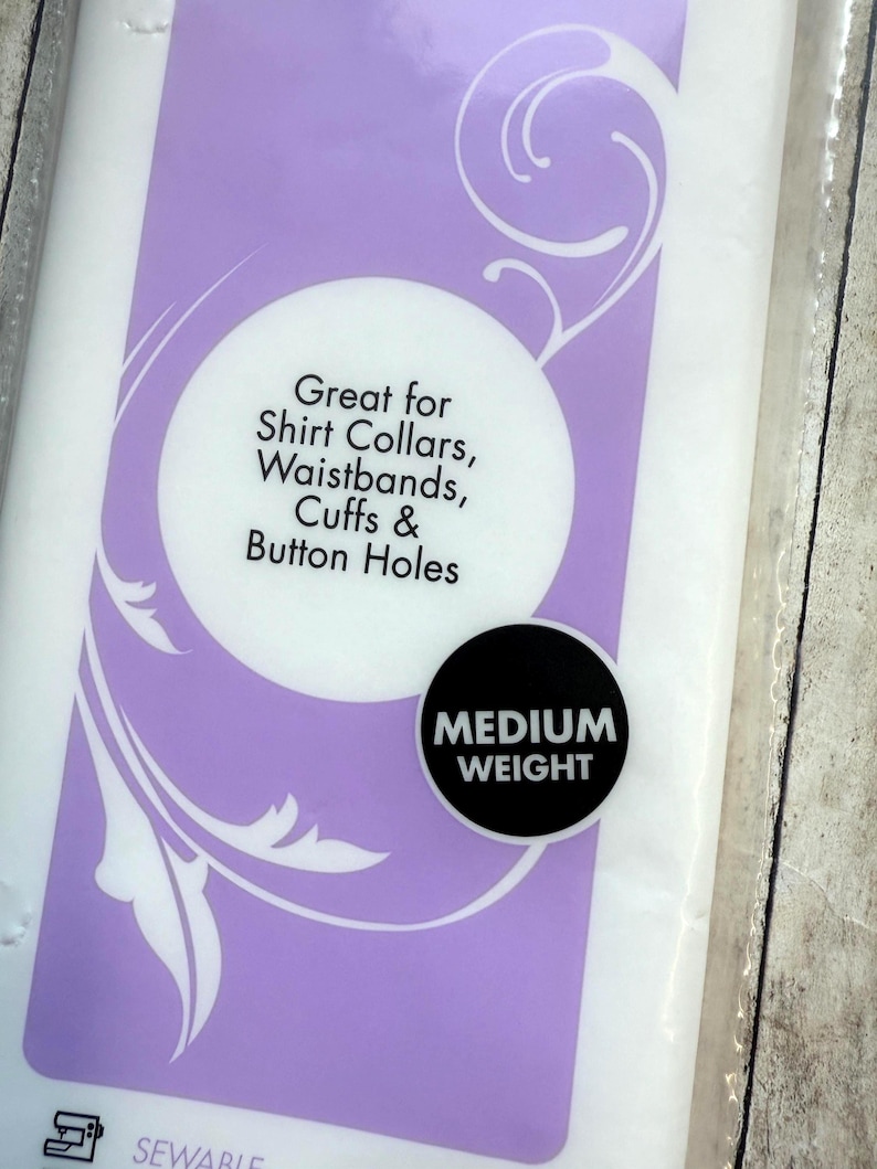 Op de afbeelding: Een verpakking van middelzware naaibare tussenvoering met een paars en wit label. De tekst op het label luidt: Great for Shirt Collars, Waistbands, Cuffs & Button Holes, en een zwarte ronde badge vermeldt: MEDIUM WEIGHT.