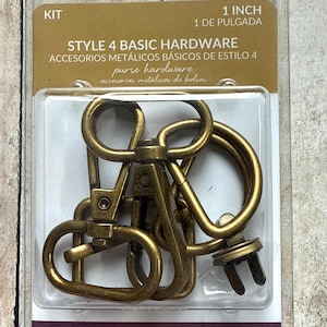 May include: A Sallie Tomato Style 4 Basic Hardware kit containing antique brass-coloured metal purse hardware, including swivel lobster clasps and D-rings, packaged in a clear plastic blister pack labelled 1 inch for bag making projects.