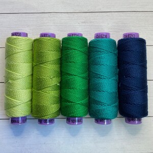 Puede incluir: Cinco carretes de hilo de bordar en tonos de verde y azul. Los carretes est&aacute;n etiquetados con los n&uacute;meros de color: Col EZ30, Col EZ34, Col EZ35, Col EZ36 y Col EZ12.