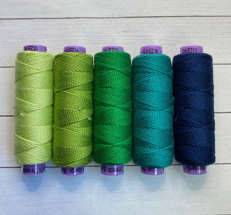 Puede incluir: Cinco carretes de hilo de bordar en tonos de verde y azul. Los carretes est&aacute;n etiquetados con los n&uacute;meros de color: Col EZ30, Col EZ34, Col EZ35, Col EZ36 y Col EZ12.