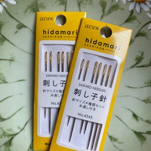 May include: Two packages of sashiko needles on a floral background. The yellow packages feature the brand name "hidamari" and Japanese text. Each package contains multiple needles, with the text "Sashiko Needles" and "Made in Japan" visible.