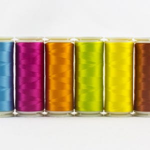 May include: Six spools of colorful thread in a row. The colors include light blue, magenta, orange, lime green, yellow, and brown. The spools are cylindrical with white bases and tops, perfect for sewing and crafting projects.