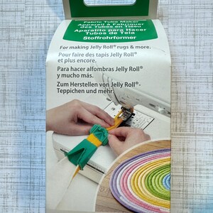 May include: A Clover brand fabric tube maker, model 4022, in a white and green cardboard box. The packaging features a yellow and green plastic tool being used with a sewing machine to create a coiled, multi-colored fabric rug.