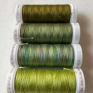 May include: Four spools of green thread. The spools are labeled "Sulky Blendables 40 wt. 112-06-39", "Sulky", "Sulky", and "Cotton Petites 12 wt. 41E311".