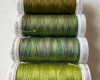May include: Four spools of green thread. The spools are labeled "Sulky Blendables 40 wt. 112-06-39", "Sulky", "Sulky", and "Cotton Petites 12 wt. 41E311".
