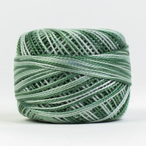 Op de afbeelding: Een bolletje garen in groen- en wittinten. Het garen is strak opgerold en toont een mix van licht- en donkergroen met witte strepen. Geschikt voor borduren, haken en andere knutselprojecten. Diameter ongeveer 5 cm.