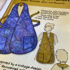 May include: A sewing pattern for a wrap front apron with two fabric prints. The pattern is reversible and features a pocket on each side. The text on the pattern reads "Wrap Front Apron Pattern" and "Another Reversible Apron with Personality".