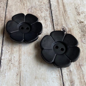 May include: Two black flower-shaped buttons with two holes each.
