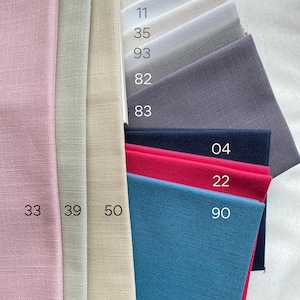 May include: A stack of fabric swatches in various colors and textures, including pink, beige, gray, blue, and red. The swatches are labeled with numbers: 33, 39, 50, 90, 22, 04, 83, 82, 93, 35, and 11.