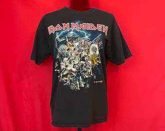 May include: Black t-shirt with a graphic print of the band Iron Maiden. The graphic features a group of figures in a dark, stormy setting.