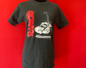 May include: Black t-shirt with a white and red graphic of a guitar and the word "Rancid" with the text "Roots Radicals" below.