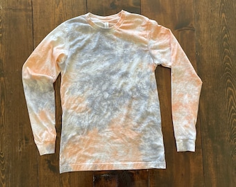 May include: A long-sleeved shirt with a tie-dye pattern in shades of peach, gray, and white.