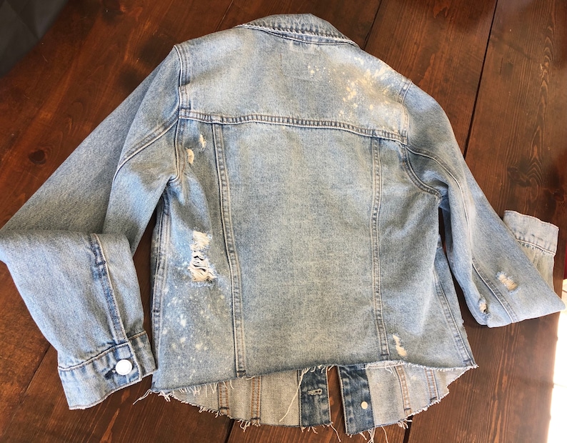 May include: Light blue denim jacket with distressed details and a frayed hem.