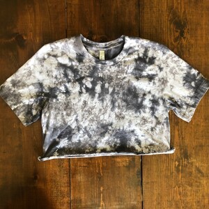 May include: A cropped, short-sleeved t-shirt with a tie-dye pattern in shades of gray and white.