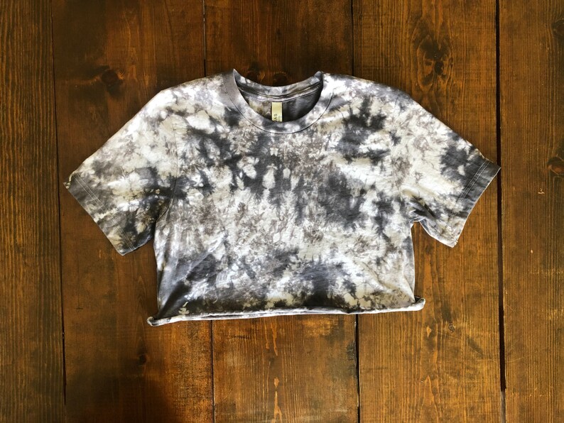 May include: A cropped, short-sleeved t-shirt with a tie-dye pattern in shades of gray and white.
