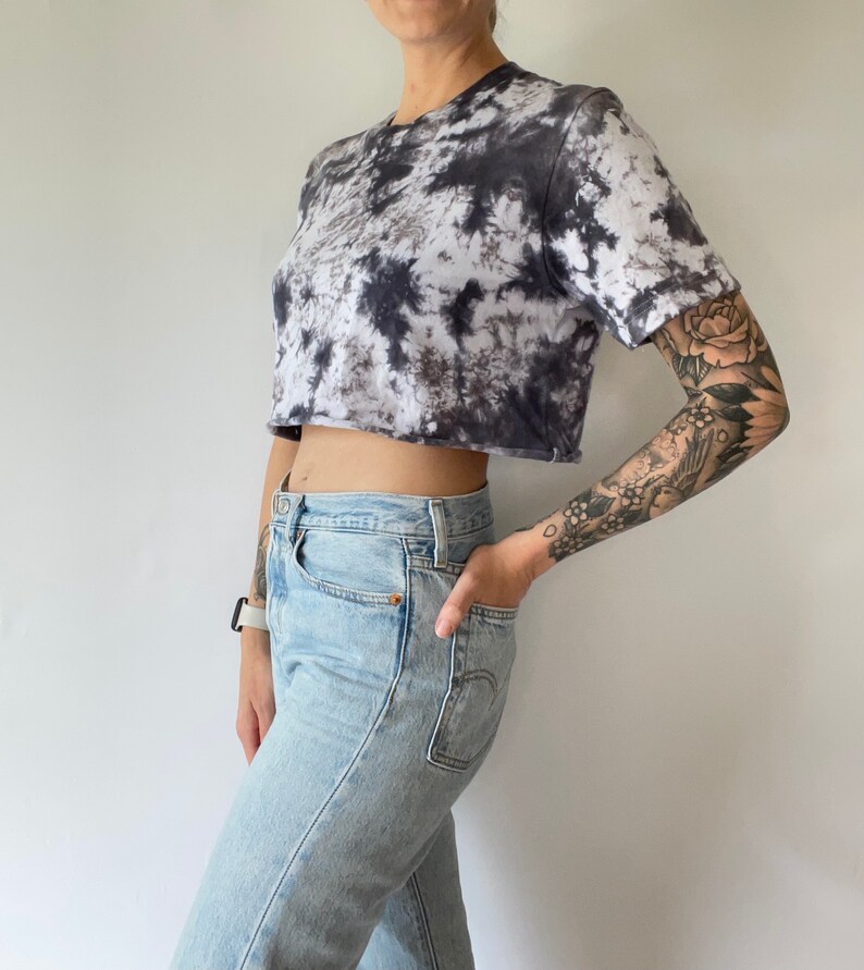 May include: A cropped tie-dye t-shirt in black and white with a relaxed fit. The shirt is made of a soft, comfortable fabric and has a crew neckline.