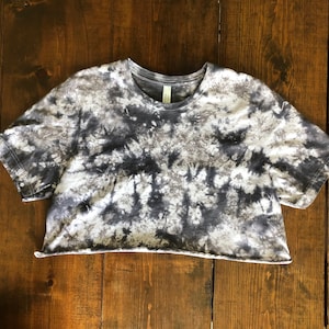 May include: A cropped, short-sleeved t-shirt with a tie-dye pattern in shades of gray and white.