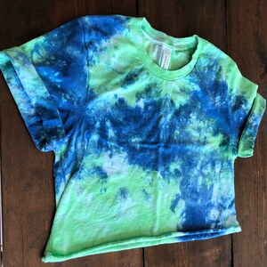 May include: A green and blue tie-dye cropped t-shirt with a crew neck.
