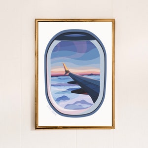 Può includere: Una stampa artistica incorniciata raffigurante una vista dal finestrino di un aereo. L'illustrazione mostra un'ala e il cielo con nuvole in tonalità di blu, viola e arancione. La stampa è in una cornice dorata e firmata "CAIA MOON".