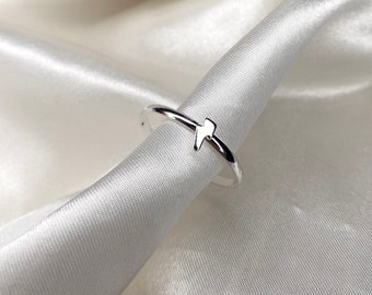 May include: A silver ring with a lightning bolt design. The ring is on a white satin background.