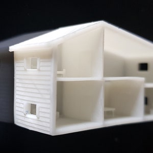 Peut inclure: Une maquette blanche d'une maison à deux étages avec un toit en pignon. La maison a un extérieur détaillé avec des revêtements et des fenêtres. L'intérieur est ouvert, montrant l'agencement des pièces et des étages. Modèle architectural miniature.