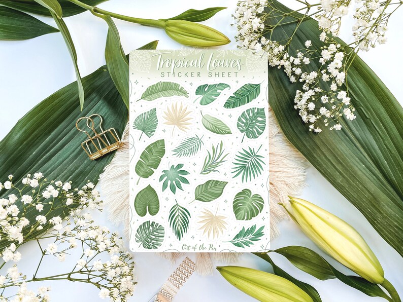 May include: A sticker sheet with a white background and a variety of green tropical leaves. The sheet is titled "Tropical Leaves Sticker Sheet" and has the text "Out of the Pen" at the bottom.