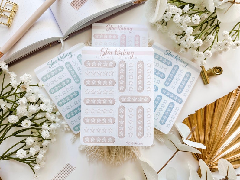 May include: Three sheets of planner stickers with star ratings. The stickers are in three colors: light blue, beige, and a darker blue. The stickers are arranged in rows of five stars, with each row representing a different rating. The text "Star Rating Planner Stickers" is printed on the top of the beige sheet.