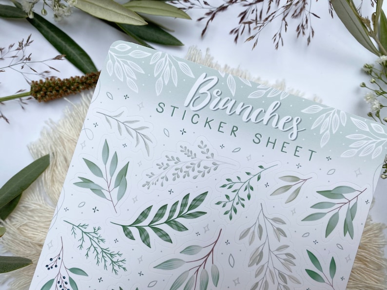 Op de afbeelding: Een stickerblad met een witte achtergrond en een groene en grijze gradi&euml;nt. Het blad bevat verschillende illustraties van takken en bladeren. De tekst "Branches Sticker Sheet" is in het zwart bovenaan het blad gedrukt.