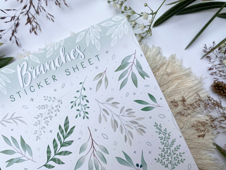 Op de afbeelding: Een stickerblad met een groene en witte gradi&euml;nt achtergrond met verschillende groene en witte takken en bladeren. De tekst "Branches Sticker Sheet" staat in cursief bovenaan het blad.