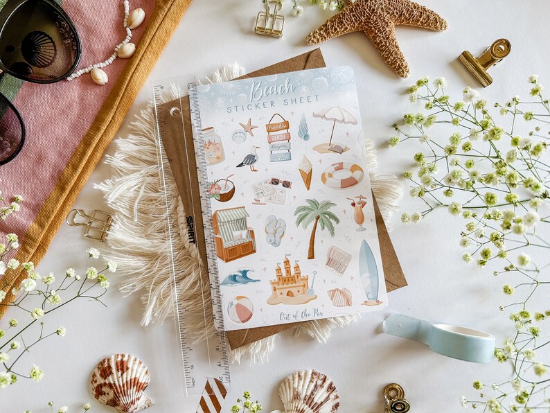 May include: A sticker sheet with a beach theme. The sheet features a variety of stickers, including a beach umbrella, a beach chair, a surfboard, a palm tree, a sandcastle, a seashell, a starfish, a coconut, a drink, and a pair of sunglasses. The sheet is titled "Beach Sticker Sheet" and has the text "Out of the Pin" at the bottom.