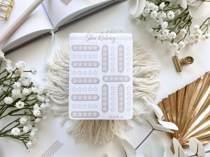 May include: A sheet of white planner stickers with a light brown background. The stickers feature various star ratings from one to five stars. The text "Star Rating Planner Stickers" is at the top of the sheet. The text "Out of the Box" is at the bottom of the sheet.