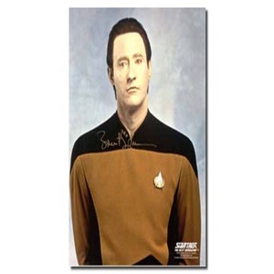 May include: A black and gold Star Trek uniform with a gold Starfleet insignia. The uniform is signed "Brent Spiner" in black ink.