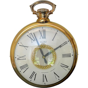 May include: A gold-colored pocket watch with a white face and black Roman numerals. The watch has a gold-colored handle and a decorative gold-colored ring around the center. The word "United" is printed on the face.